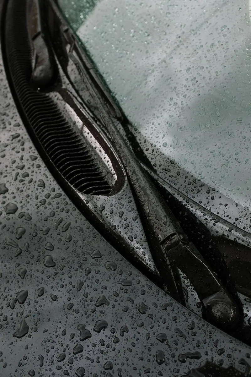 Water beads on black glass beside a wiper