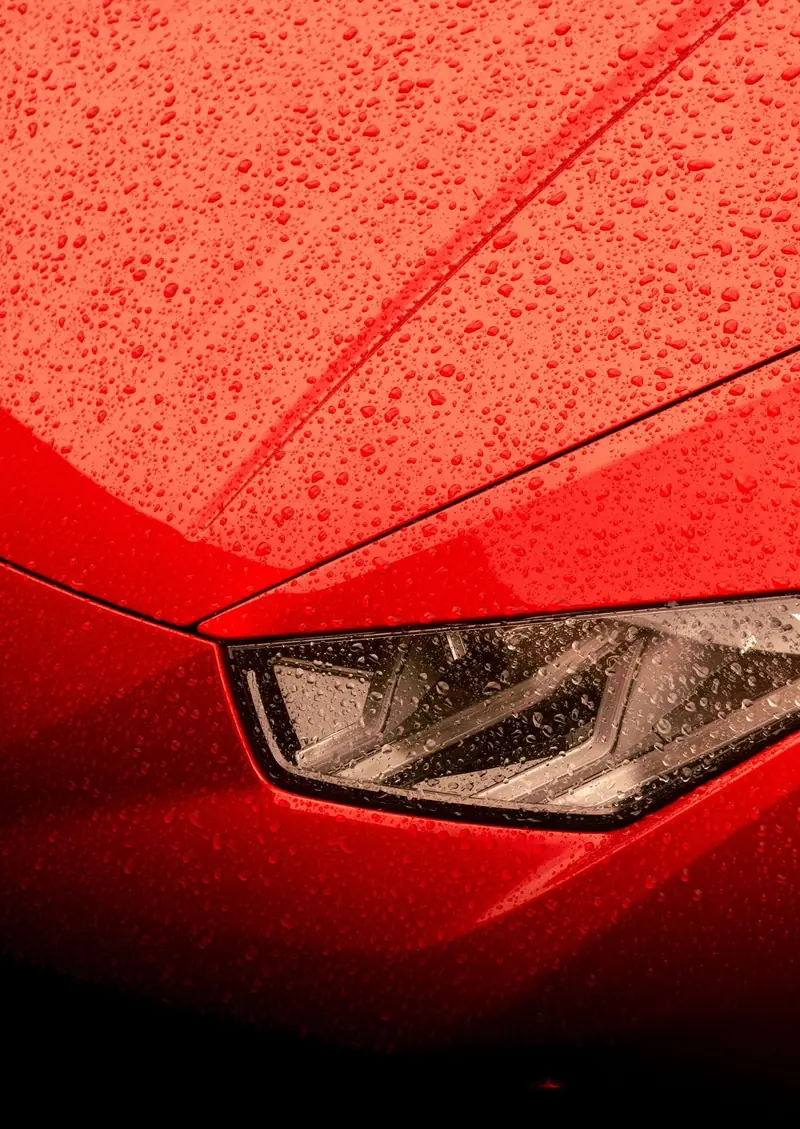 Water beading on a red hood beside the headlight