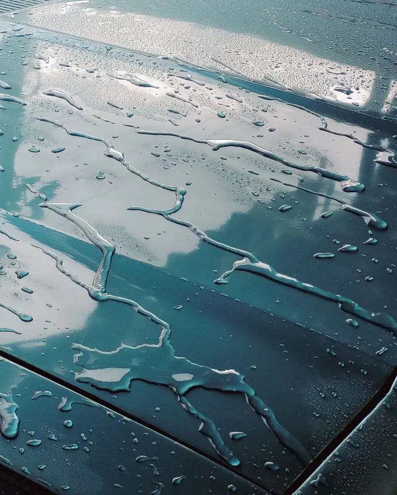 Water sheeting off a coated teal hood