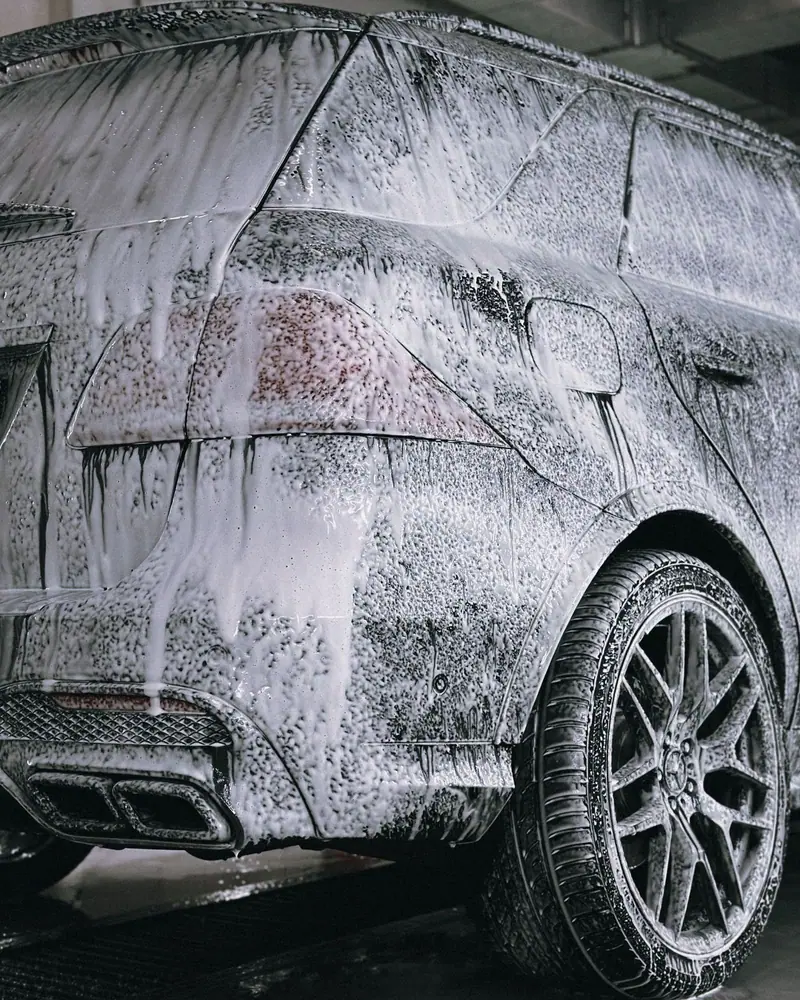 SUV covered in wash foam beside its wheel