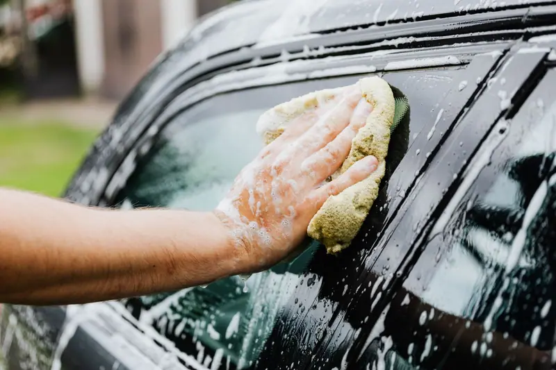 Soapy sponge washing a car window by hand