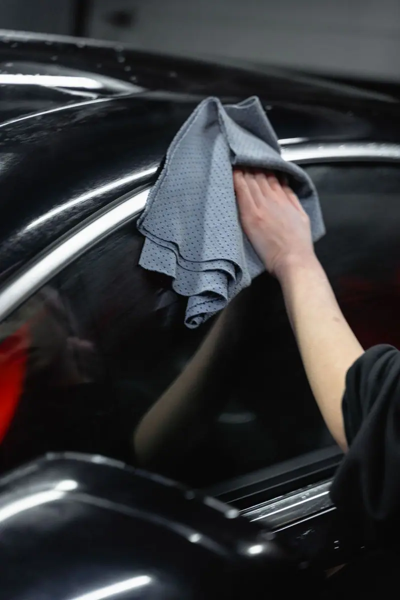 Grey microfiber towel drying a black car pillar