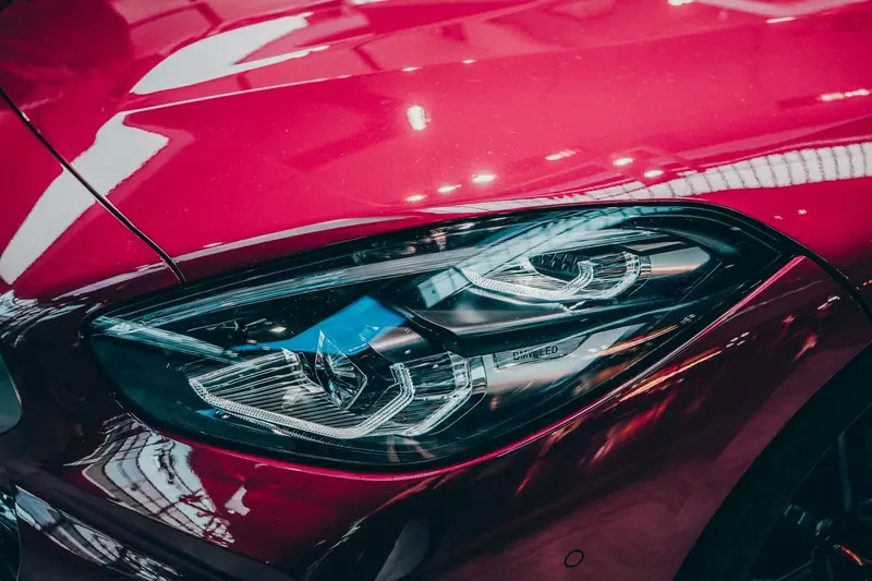 Clear LED headlight on a red car, close up