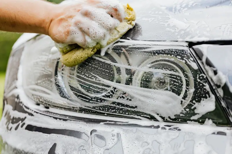 Headlight being washed with a soapy sponge