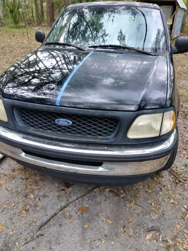 Older Ford F-150 hood taped down the middle: one half polished to a gloss, the other half still dull