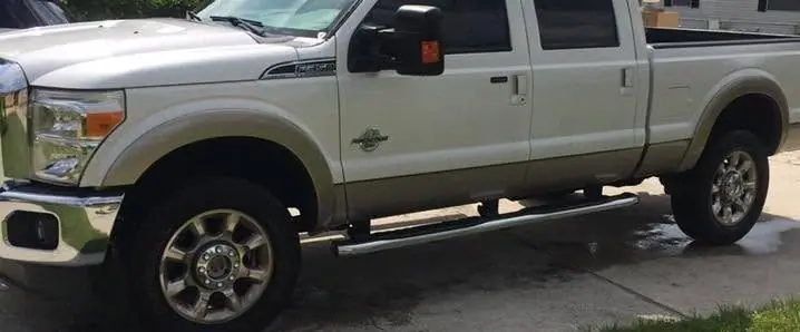 Silver and tan Ford Super Duty pickup in a driveway before its wash