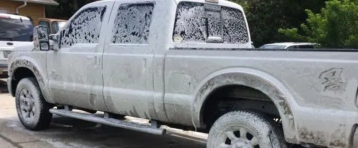 Ford Super Duty pickup covered in wash foam in a driveway
