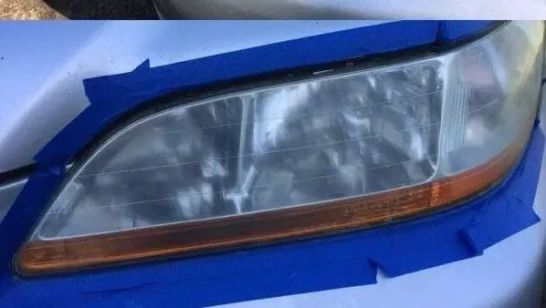 Headlight taped off with blue painter tape, ready for restoration
