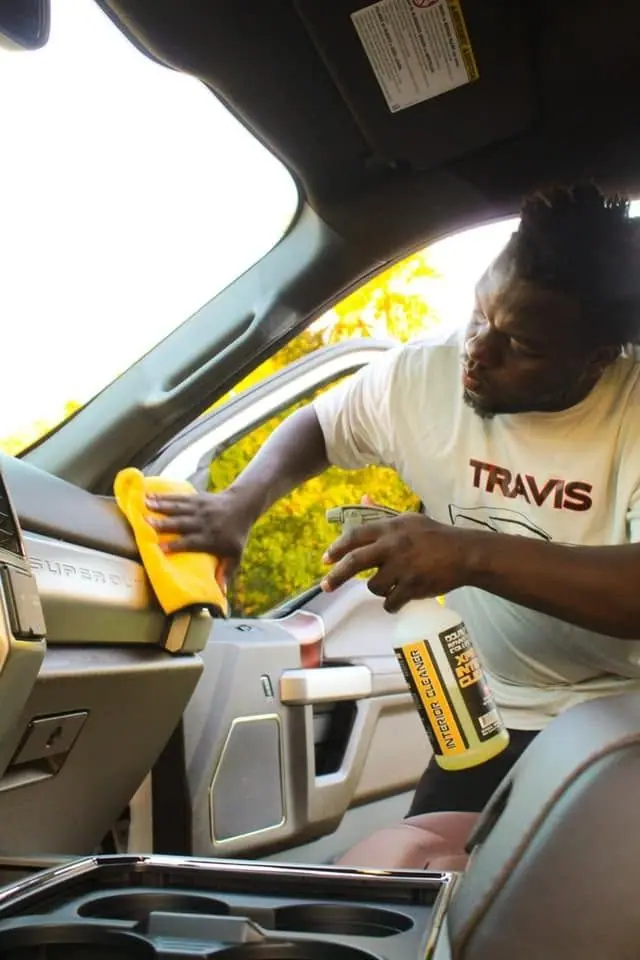 Crew member wiping down a pickup truck console during an interior detail