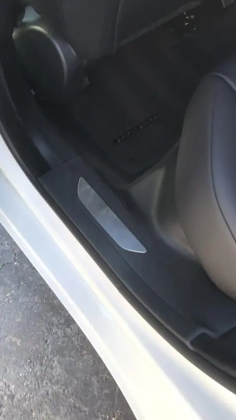Clean door sill and floor mat inside a white car after an interior detail