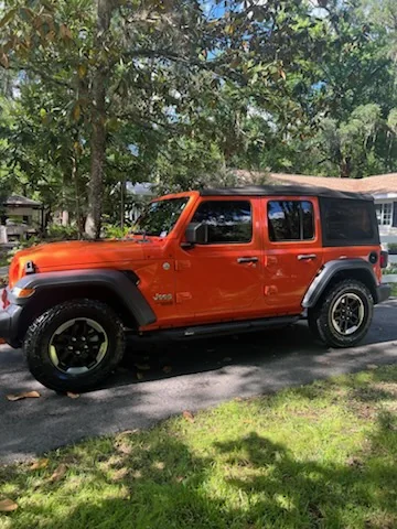 Bright orange Jeep Wrangler shining in a driveway after a detail