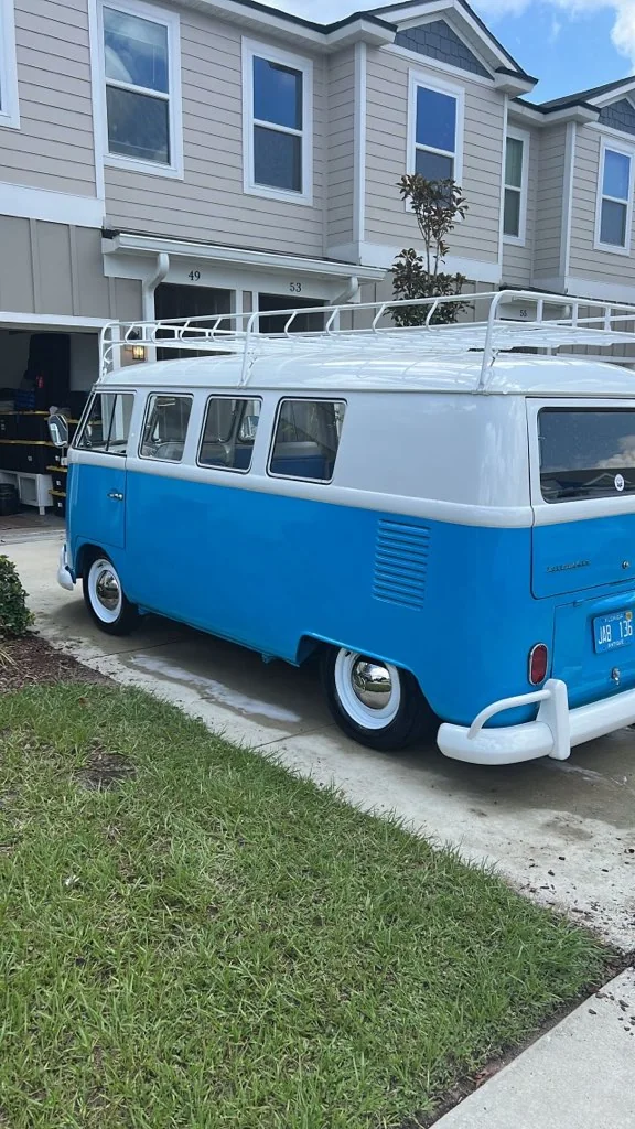 Blue and white vintage Volkswagen bus parked on a driveway after a detail